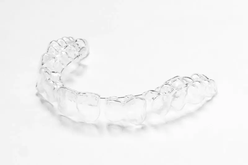Aligneur orthodontique transparent posé seul sur une surface blanche, photographié en lumière douce
