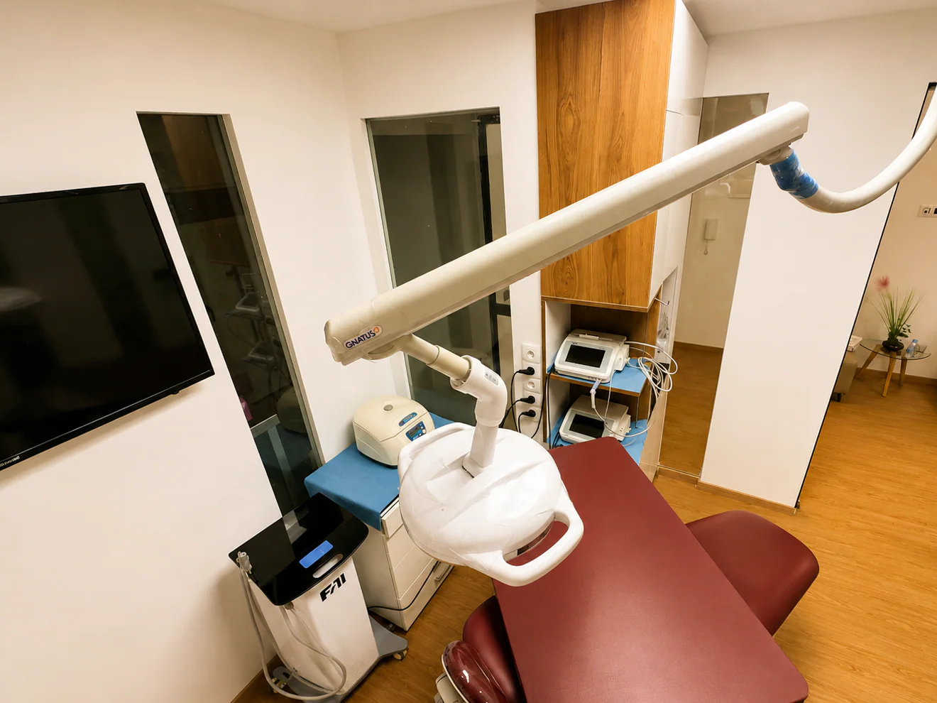 Salle de soins avec fauteuil bordeaux, scialytique et écran