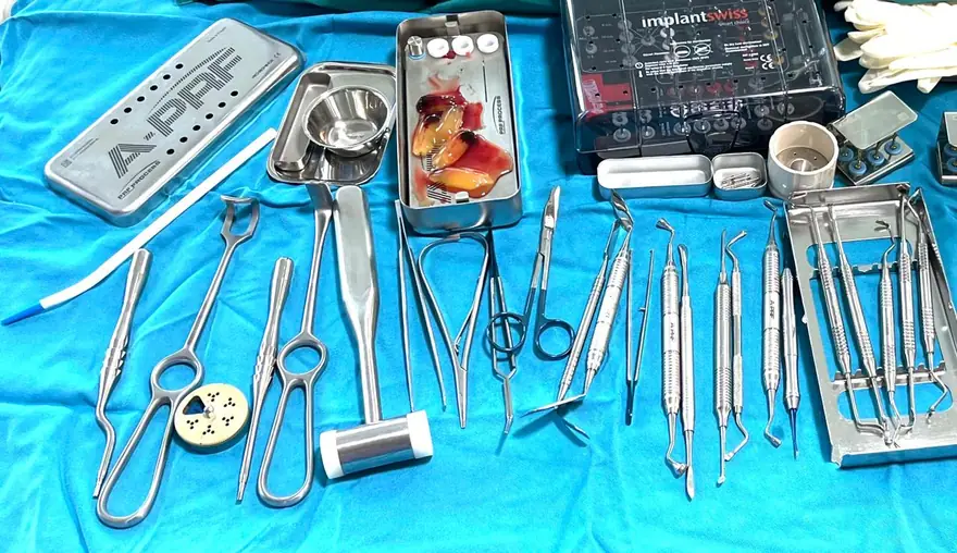 صينية جراحية كاملة على قماش فيروزي: علبة PRF Process المعدنية، وعلبة مثاقب implantSwiss، وأدوات تحمل علامة A-PRF، وفي الوسط علبة مفتوحة تحتوي عدة أغشية فيبرين بلون العنبر.