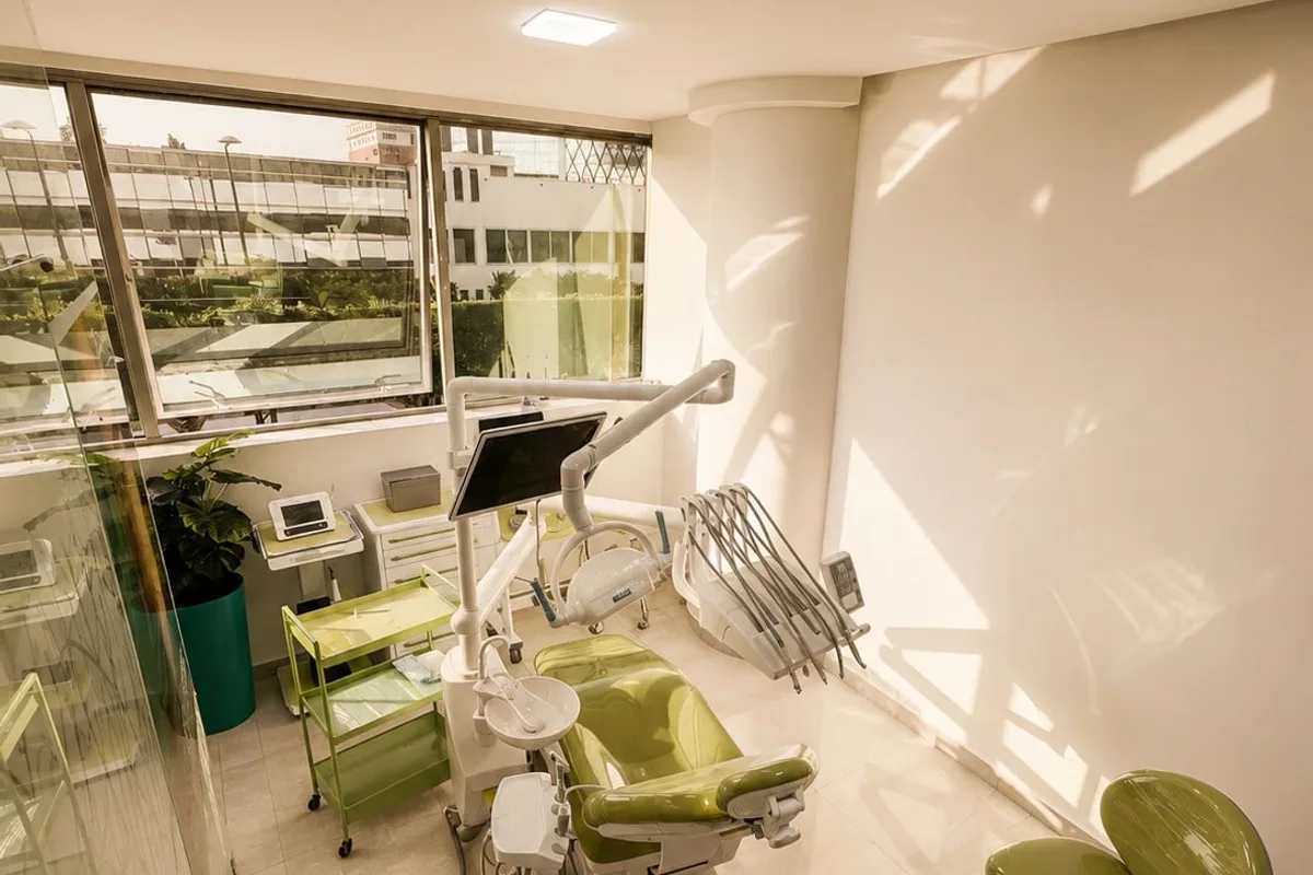 Salle de soins du cabinet à Kénitra : fauteuil dentaire vert, lumière naturelle