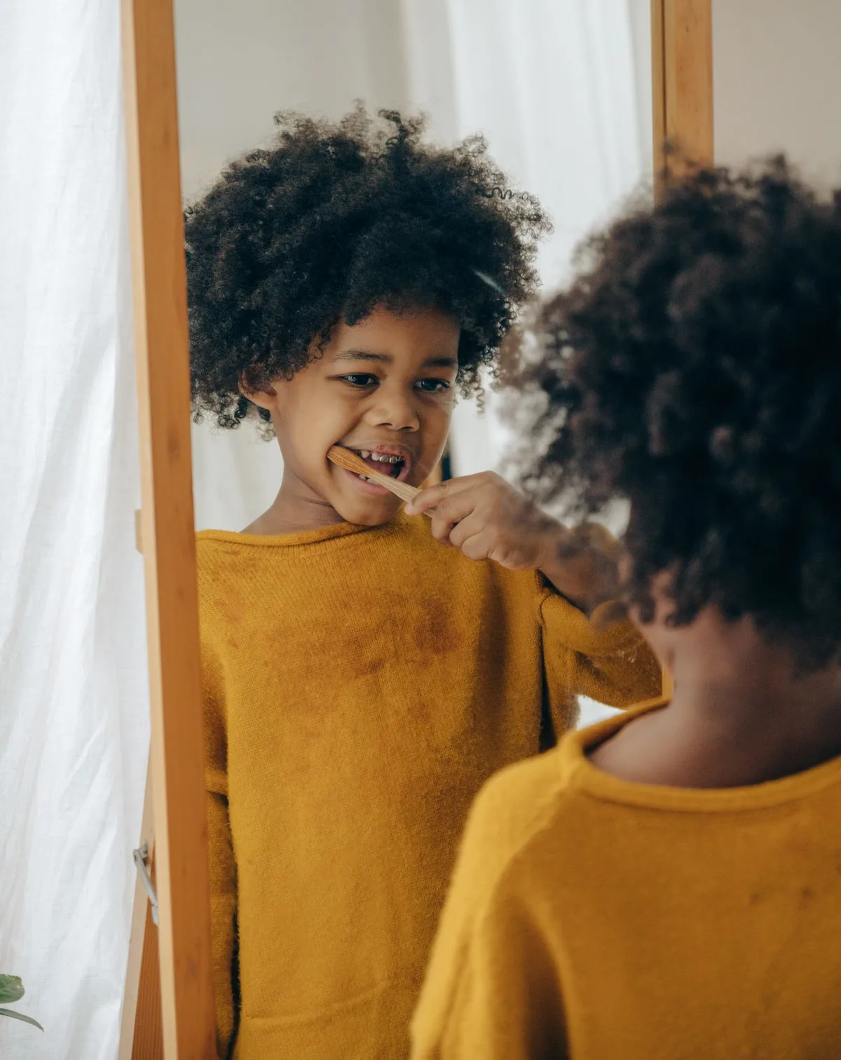 Un enfant se brosse les dents devant un miroir