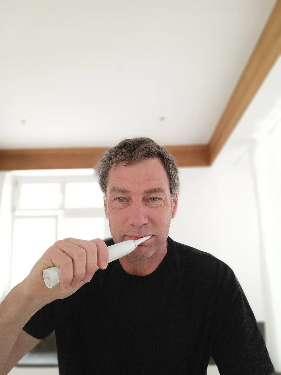 Un homme utilise une brosse à dents électrique
