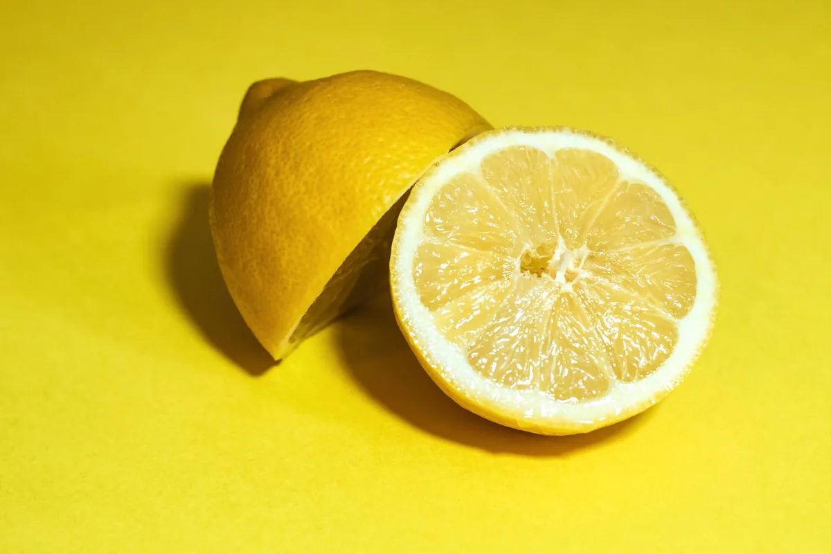 Citron entier et moitié de citron sur fond jaune