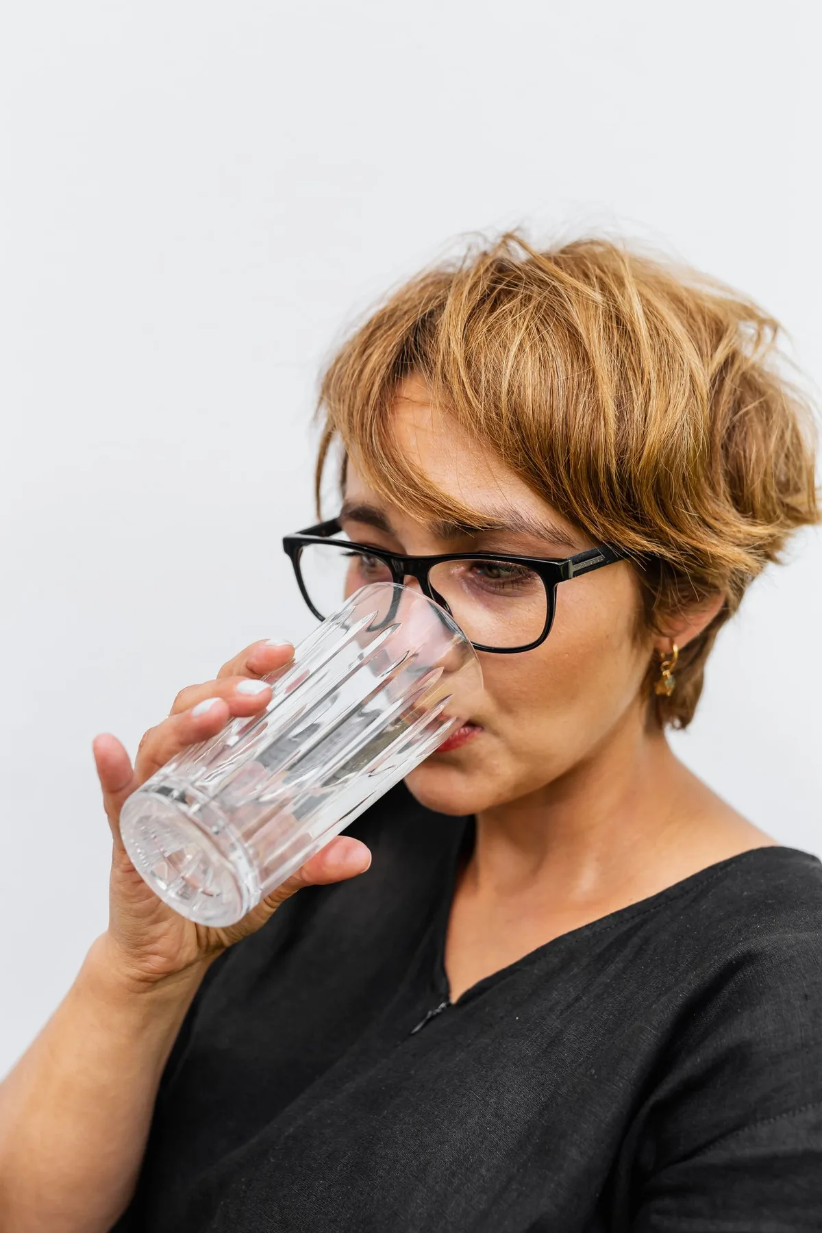 Une femme boit un verre d’eau : photographie avec modèle