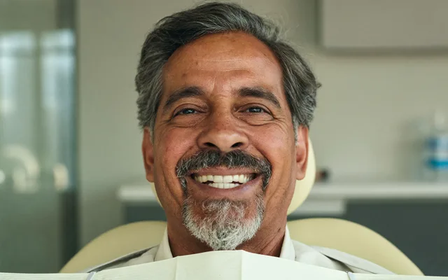Homme souriant en fauteuil dentaire après son traitement