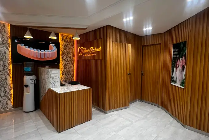 Comptoir d'accueil du cabinet avec l'enseigne lumineuse Fatima Azelmat Dental Center à Kénitra