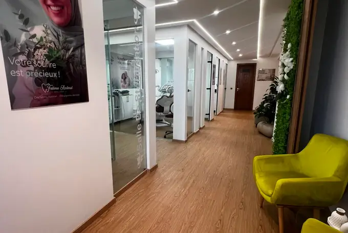 Couloir du cabinet avec parquet clair, mur végétal et canapé vert olive à Kénitra