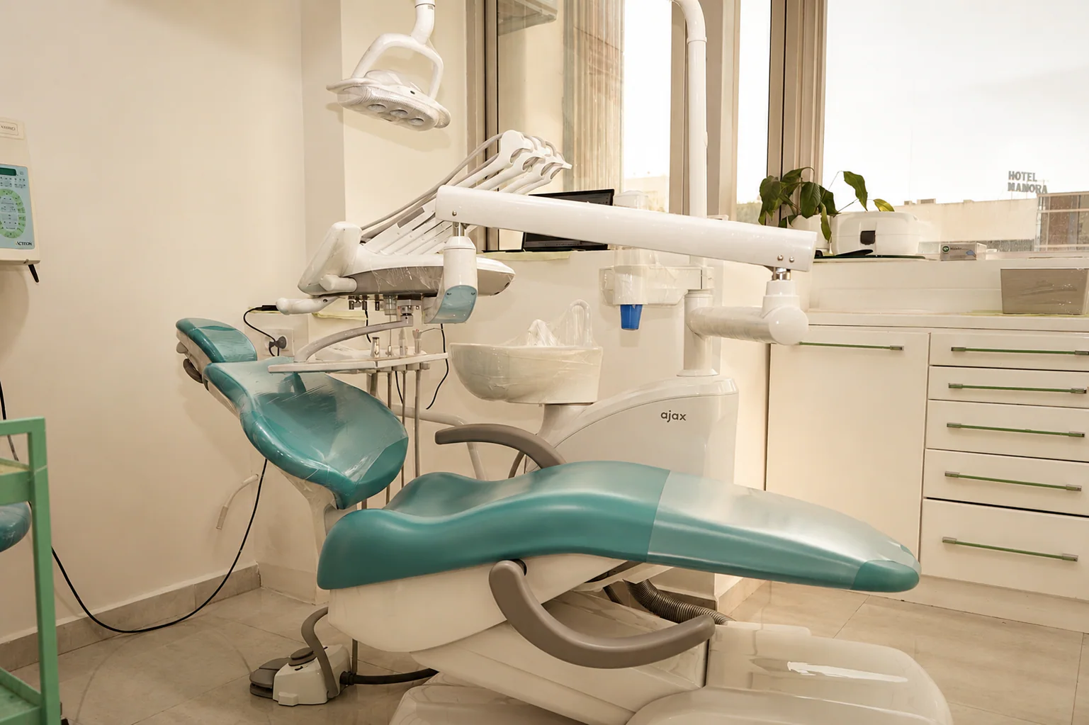 Fauteuil turquoise et unit dentaire dans une salle de soins lumineuse du cabinet à Kénitra