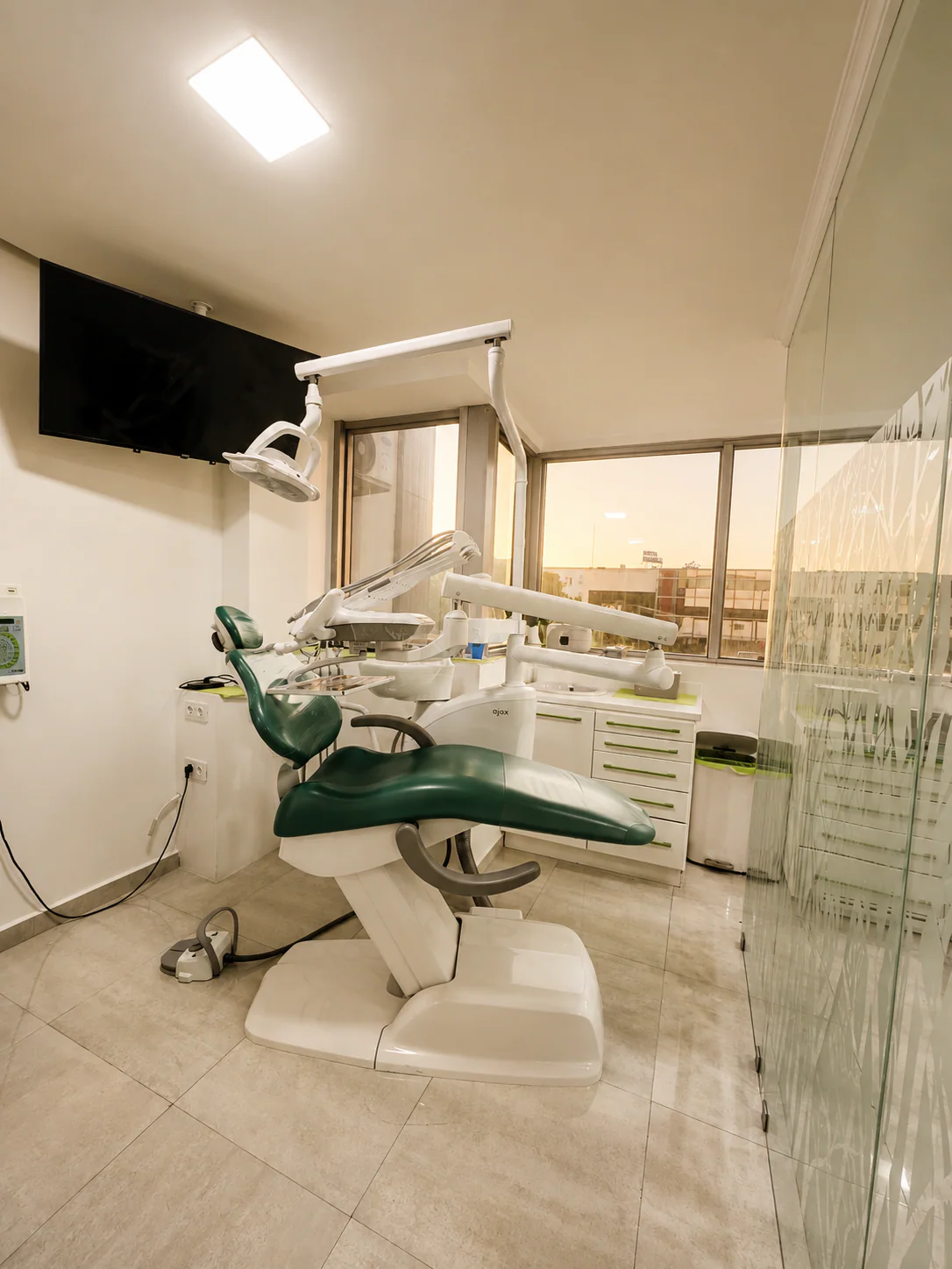 Fauteuil dentaire vert, écran mural et instruments dans une salle de soins lumineuse à Kénitra
