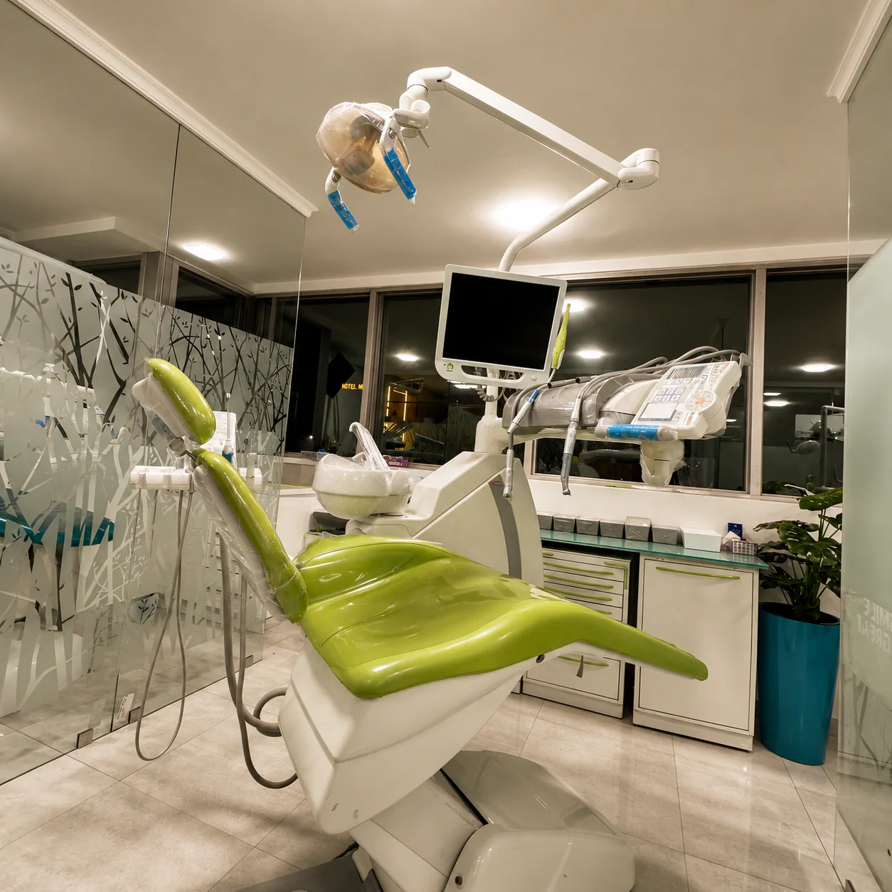 Salle de soins équipée d'un fauteuil vert, d'un écran et d'un scialytique au cabinet à Kénitra