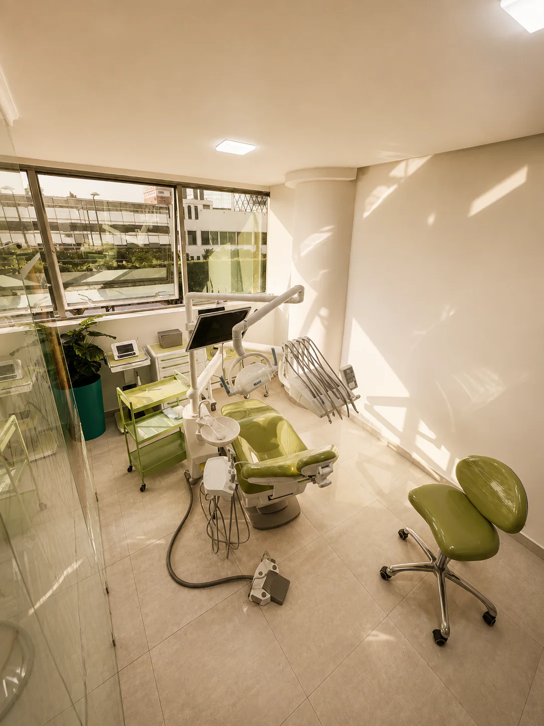Salle de soins avec fauteuil vert, console dentaire et grande fenêtre au cabinet à Kénitra