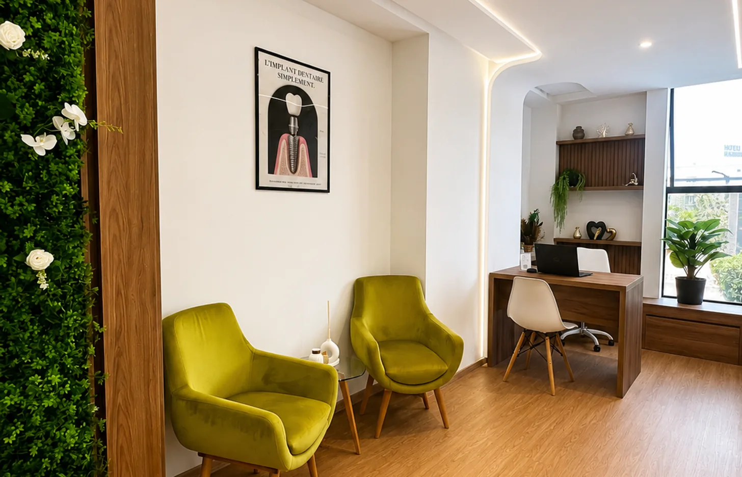 Salon d'attente du cabinet dentaire avec fauteuils verts et mur végétal à Kénitra
